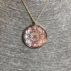 "Sri Yantra pendant in 24 carat gold on 925 silver and rose natural mother of pearl backdrop. It's one of the most powerful symbol in sacred geometry, belonging both to Induism and Buddhism traditions. It has a complex structure made of nine interlocking triangles: four of them, looking upside, show male power and Shiva, five of them, looking down side, express a female Energy and her Goddes Shakti. These 43 triangles represent the cosmos and the human body, they surround a point known as bindu, Spiritual Rose Gold Locket Necklace, Pink Medallion Jewelry As A Gift, Pink Medallion Jewelry For Gifts, Pink Medallion Jewelry Gift, Pink Gold Necklace With Polished Finish For Gift, Pink Jewelry For Meditation, Spiritual Medallion Necklace With Polished Finish, Pink Amulet Necklace For Gift, Pink Engraved Pendant Jewelry