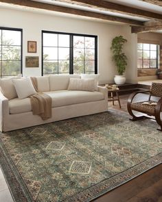 a living room with a couch, chair and rug on the floor in front of large windows