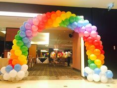 an arch made out of balloons in the middle of a room with tables and chairs