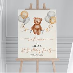 a welcome sign for a baby's 1st birthday party with balloons and a teddy bear