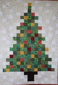 a quilted christmas tree is hanging on the wall