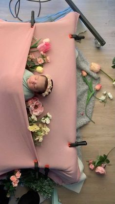 a baby is laying in a pink bed with flowers on the floor next to it