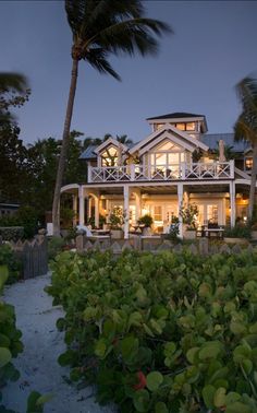 a large white house sitting on top of a lush green field next to palm trees