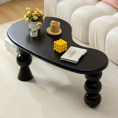 a black table with yellow flowers on it in front of a white couch and coffee table