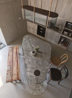 an aerial view of a kitchen and dining room with marble counter tops, wooden chairs, and stainless steel appliances