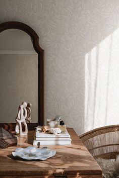 a wooden table sitting under a mirror next to a white vase on top of it