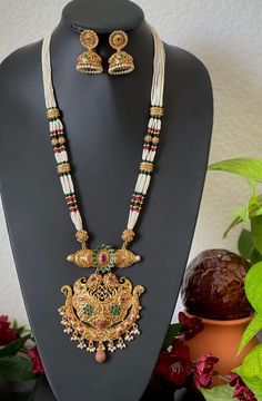 An elegant set for your local gatherings or parties. The length of the pendant necklace is given in one of the pictures. Measurements of the jhumkas. Height: 4 Cm  Width : 2.5 Cm  Care Instruction : Avoid Heat & Chemicals Like Perfume, Deo, Alchol, Etc. | Clean With Dry Cotton Cloth | Pack In our Anti tarnish box after use. Pearl Necklace With Latkans For Festivals, Festive Pearl Necklace With Latkans As A Gift, Elegant Pendant Temple Necklace With Latkans, Elegant Temple Necklace With Pendant Latkans, Festival Gift Jewelry Set With Pearl Chain, Elegant Chandbali Pearl Necklace For Puja, Elegant Long Kundan Necklace For Puja, Kundan Pearl Chain Necklace For Gift, Kundan Temple Jewelry Necklace With Pearl Chain