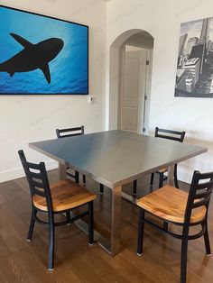 a dining room table with four chairs and a shark painting on the wall above it