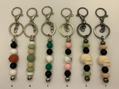 six different key chains with beads and charms attached to each one's sides on a white surface