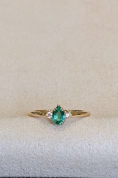 Elevate your style with our stunning 18K yellow gold Three Stone Ring, featuring a captivating 0.30 Ct. emerald flanked by radiant diamonds. This modern design embodies the essence of glamour and sophistication, setting new trends in jewelry fashion. Whether it's a gift for a special someone or a self-indulgent treat, this non-traditional gemstone ring is a symbol of elegance and refinement. Embrace the beauty of custom jewelry and make a statement with this exquisite piece that transcends traditional norms. Elegant 14k Gold Emerald Ring For Proposal, Classic White Gold Emerald Ring For Proposal, Elegant Proposal Emerald Ring With Brilliant Cut, Fine Jewelry Pear-shaped Emerald Ring Vvs Clarity, Fine Jewelry Pear-shaped Emerald Ring With Vvs Clarity, Timeless Emerald Ring As Promise Ring, Classic Emerald Diamond Promise Ring, Timeless Diamond Emerald Ring For Promise, Elegant Yellow Gold Emerald Ring For Proposal