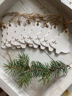 white ceramic ornaments in a box with pine branches and twine on the table top