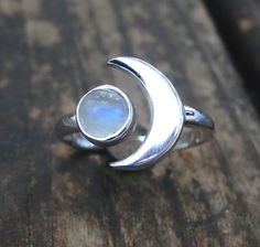 Handmade, Natural Rainbow Moonstone Sterling Silver Ring 💙Featured in this listing are sterling silver, handmade, natural stone rings. These lovely rings feature a beautiful, Natural Rainbow Moonstone 7mm round stone. The Glowing stone has been bezel set into a handcrafted, adjustable setting made with all highly polished Sterling Silver. A handcrafted Crescent Moon sits aside the Moonstone and is 11x15mm. Each Rainbow Moonstone has been handpicked, and have amazing flash! 🌜Please keep in mind Crescent Moonstone Ring For Anniversary, Crescent Moonstone Anniversary Ring, Silver Moonstone Ring With Moon Phase, Silver Moonstone Ring With Moon Charm As Gift, Crescent Moonstone Promise Ring, Silver Moonstone Crystal Ring In Moon Shape, Crescent Moonstone Ring For Gift, Celestial Moon Shaped Moonstone Crystal Ring, Celestial Moon-shaped Moonstone Crystal Ring