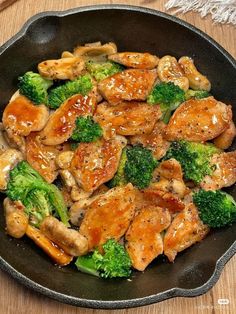 chicken and broccoli stir frying in a skillet on a wooden table