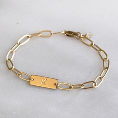 This stunning personalized bracelet is meaningful and stylish. This dainty bracelet is handmade with silver or gold chain and your initial or symbol. It makes a wonderful gift for her for any occasion. D E T A I L S *Thick 16mm bar *Paperclip chain *100% 14kt Gold-Filled JUST FOR YOU *Stamped by hand with an initial in classic block. *See our chart for available symbols. *Satin finish. LENGTH Fits most sizing: 6.0 inches extra small 6.5 inches small 7.0 inches medium 7.5 inches large HOW TO PERS Stamp Bracelet Ideas, Personalized Gold Sterling Silver Bracelets, Personalized Sterling Silver Gold Bracelet, Trendy Gold Name Bracelet For Personalized Gift, Personalized Gold Sterling Silver Name Bracelet, Minimalist Gold Charm Bracelet For Friendship, Trendy Personalized Chain Bracelet As A Gift, Trendy Personalized Chain Bracelet Gift, Personalized Sterling Silver Gold Bracelets