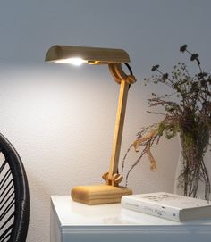 a wooden desk lamp sitting on top of a table next to a vase with flowers