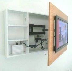 a tv mounted to the side of a white wall next to a wooden framed object