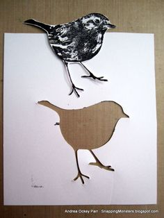 two cut out birds sitting on top of a piece of paper with one bird standing next to the other