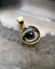 Lover's Eye pendant with an oil painting encased in gold plate over sterling with a quartz crystal cabochon which gives a magical magnifying effect, measuring 1/2" in diameter; 18" 16k gold over brass chain included. THE HISTORY: Lover's Eyes were a jewelry trend c.1785-1830 of brooches set with tiny watercolor portraits on ivory. Since they were cropped to eyes, they were in many ways more direct and intimate than traditional miniature portraits; but also because they were just eyes, they were Round Pendant Jewelry With Rotating Bezel Gift, Gold Sterling Silver Jewelry With Cabochon, Rotating Bezel Round Pendant Jewelry As A Gift, Amulet Style Round Pendant Jewelry For Memorial, Gold Spiritual Jewelry For Keepsake, Memorial Amulet Jewelry With Round Pendant, Gift Jewelry Medallion With Rotating Bezel, Medallion Jewelry With Rotating Bezel For Gifts, Unique Gold Cabochon Jewelry