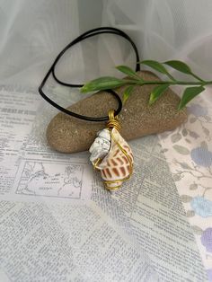 This simple but elegant necklace is made from a speckled seashell that is wire wrapped and hung on an 18" wax cord necklace with a 2" extension chain for adjusting the size. It also has white howlite crystal chips attached. It makes the perfect addition to any summer outfit and any beach day! Howlite is a borate mineral known for its chalky white appearance with dark veins, symbolizing patience and perspective. It serves as a calming stone, soothes the body, mind, and spirit, promoting wisdom, r Gold Wire-wrapped Necklaces For The Beach, Gold Wire Wrapped Necklace For The Beach, White Necklace With Adjustable Waxed Cord, Wire Wrapped Shell Necklaces In Shell Shape, Wire Wrapped Shell Necklaces, White Shell Necklace With Adjustable Cord As Gift, Adjustable Wire Wrapped White Jewelry, Adjustable White Wire Wrapped Jewelry, Handmade White Jewelry With Waxed Cord