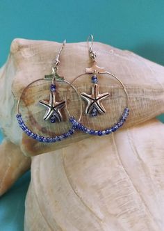 Ocean Tides and Waves Sapphire Blue Beaded Starfish Earrings. Blue glass seed beads strung on a silver colored hood. Starfish charm position in the center of hoop. These are a must for beach trip or any summer vacation event. Makes a great gift. Starfish-shaped Beaded Beach Jewelry, Blue Starfish Charm Jewelry For The Beach, Blue Starfish Charm Jewelry For Summer, Blue Summer Jewelry With Starfish Charm, Summer Blue Starfish Charm Jewelry, Blue Star Shaped Jewelry For Vacation, Blue Star Jewelry For Vacation, Handmade Blue Jewelry For Beach Season, Starfish-shaped Beaded Jewelry For The Beach