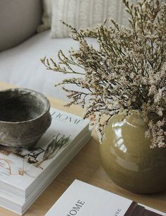 there is a vase with some flowers in it on the table next to two books