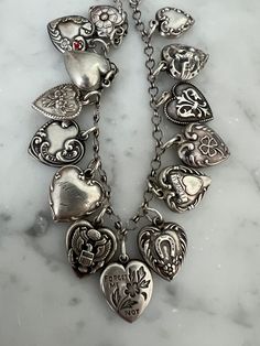 Offered here is the most amazing fully loaded Victorian era 3-D engraved heart charm bracelet. This bracelet has many coveted 3-D heart charms, almost all have intricate designs, some with flowers or military design, horseshoe, clover etc...and several have engraved initials etc-see photos and video for more details. The heart with red enamel and hearts and flower motif has the Walter Lampl stamp, the other hearts are stamped sterling. I do not have any history on this piece, but these bracelets were popular in the Victorian era to engrave family members initials etc. I believe one charm on this bracelet is engraved "son" and others with names or initials.   Length is approx 7 1/4" although links could be added or subtracted.  Weight is approx 22.6 grams.  Check out my other listings for o Antique Bracelets With Dangling Charms As Gift, Antique Bracelets With Dangling Charms For Gift, Antique Style Bracelets With Dangling Charms As Gift, Antique Charm Bracelet Jewelry, Antique Charms Bracelet Jewelry, Heirloom Charms Jewelry For Collectors, Ornate Vintage Charm Sterling Silver Jewelry, Ornate Vintage Sterling Silver Jewelry, Antique Silver Engraved Jewelry For Valentine's Day