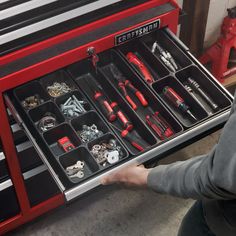 a man is holding a tool drawer full of tools and screwdriver's