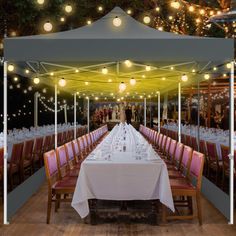 a long table is set up with white linens and lights strung from the ceiling