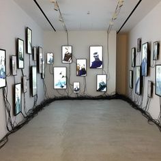 an empty room with multiple frames on the wall and wires running down the floor in front of them