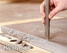 a person using a pair of scissors to cut tile on the floor with a piece of wood