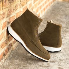 a pair of brown suede boots sitting on top of a stone wall next to a brick wall