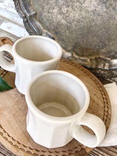 two white cups sitting on top of a wooden tray