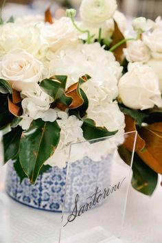 white flowers in a blue and white vase with an acrylic name on it