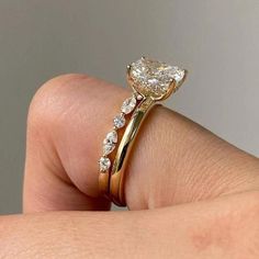 a woman's hand holding a gold ring with a heart shaped diamond