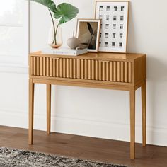 a wooden table topped with a plant next to a framed photo on top of it