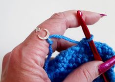 a woman's hand holding a crochet hook with a ring on it