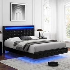 a bedroom with white walls, black furniture and blue lights on the bed headboard