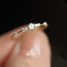 a person holding a tiny diamond ring in their hand