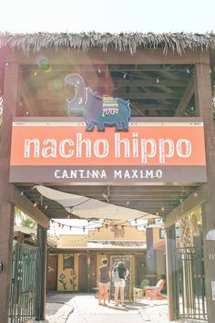 the entrance to macho hippo in cancuna, mexico with people standing under it