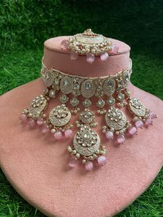 Adorn yourself in timeless elegance with this exquisite pink Kundan and zircon necklace set, perfect for weddings and special occasions. Crafted with meticulous attention to detail, the set features delicate pink hues reminiscent of Pakistani and Punjabi traditions, with a touch of Bollywood glamour. Complete with matching earrings and a stunning maangtika, this Indian Kundan ensemble effortlessly captures the essence of sophistication and grace. Measurements:   Necklace Length-14" Necklace Width- 9" Centre piece length -3.5" Earring Length-2.5" Earrings width-1.5" Each earring weighs: 18gms   Maangtika Length- 7" Maangtika Width- 1.5" Pink Cubic Zirconia Wedding Jewelry, Pink Diamond Jewelry With Stone Setting, Elegant Meenakari Bridal Sets For Eid, Traditional Cubic Zirconia Bridal Necklace For Reception, Traditional Bridal Sets With Simulated Diamond For Wedding, Traditional American Diamond Bridal Sets For Wedding, Elegant Pink Bridal Necklace For Festive Occasions, Pink Kundan Necklace For Festive Reception, Kundan Necklace With American Diamond Stone Work For Weddings