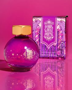 a purple perfume bottle next to a pink box