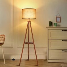 a wooden floor lamp next to a white dresser