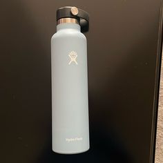 a water bottle sitting on top of a table next to a black surface with the word hydro flask printed on it