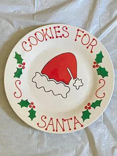 a plate that says cookies for santa on it with a santa's hat and holly