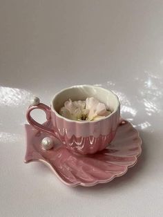 a pink tea cup and saucer with flowers in it