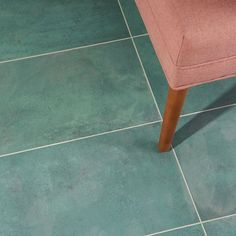 a pink chair sitting on top of a green tile floor