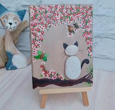 a cat sitting on top of a wooden easel next to a stuffed animal bear