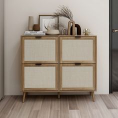 a wooden cabinet with two doors and some vases on top of it next to a black door