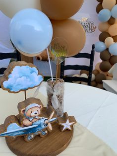 a teddy bear is sitting on top of a small plane with balloons in the background