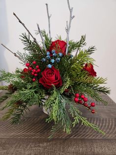 a vase filled with red roses and greenery